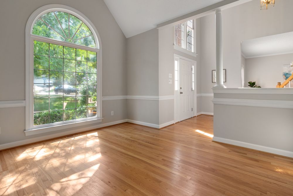 A bright Altadore room with light oak flooring and an arched window.