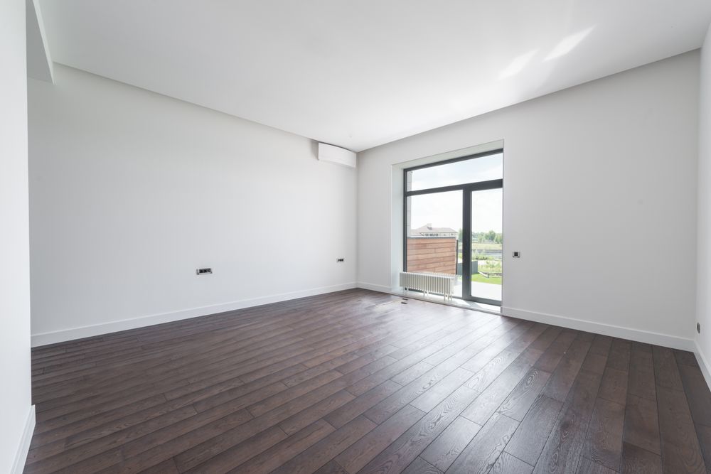 An empty Renfrew room with dark wood flooring and plain walls.